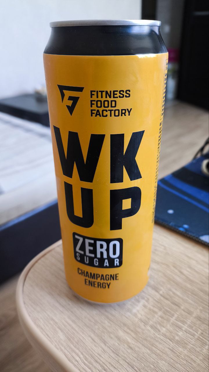 WK UP Champagne Energy Drink, Zero Sugar Erotic Delight A vibrantly yellow energy drink can, prominently featuring "WK UP" and "ZERO SUGAR CHAMPAGNE ENERGY," poised on a light wooden surface, beckoning for a taste of its stimulating elixir.